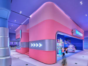 A vibrant game center with pink and blue lighting, featuring a bright, colorful environment with game machines and a playful 