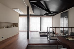 A modern indoor space featuring wooden flooring, minimalist furniture, and natural light through multiple windows.