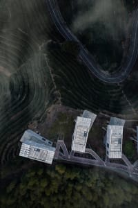 Aerial view of modern tea farm buildings surrounded by terraced tea plantations.