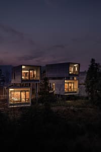 Modern residential house with glass exterior walls illuminated at night.