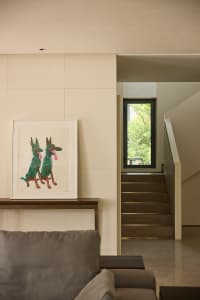 Modern living room with concrete walls and wooden stairs, featuring a framed picture of dogs on the wall.