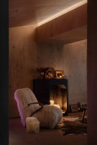 Industrial-style lounge area featuring a wooden armchair, candles, and framed artwork.