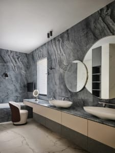 A modern bathroom featuring marble walls and a floating vanity with double sinks.