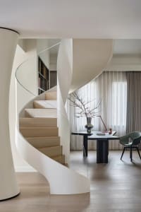 A modern residential office featuring minimalist design elements, including a spiral staircase, a desk, and a chair.