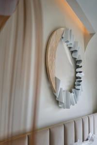 A modern, curved wooden wall object with white ribbons attached.