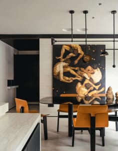 A modern dining room with a large, dark wood table surrounded by orange chairs, featuring a large abstract artwork depicting 