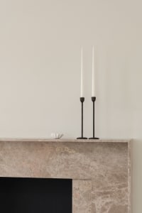 Minimalist marble fireplace with sculptural design and tall candlesticks