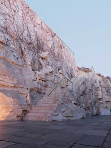 Stairs made of stone leading up a rocky hillside under a clear sky.