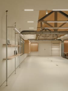 A minimalist modern interior space featuring wooden shelves and a vaulted ceiling with exposed beams.