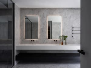 Modern bathroom with marble walls and flooring, featuring a minimalist design with floating vanity and double sinks.