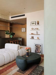 A modern living room with soft furniture, wooden shelves, and a patterned rug