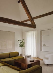 A minimalist living room featuring a modern sofa, wooden coffee table, and a large window with sheer curtains.