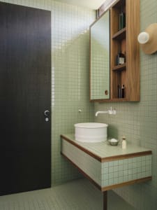 Modern bathroom featuring green tiles with industrial style elements.