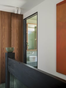 A modern bathroom with blue tiles and wooden elements.