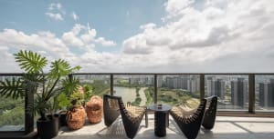 A modern balcony featuring concrete furniture, plants in pots, and a view of a cityscape.