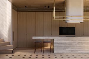 A modern residential kitchen featuring wooden cabinets, marble countertops, and brass handy fasteners.