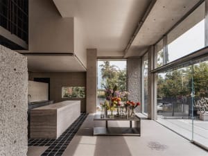 A modern, maximalist weight room featuring concrete and glass elements.