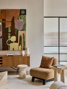 A modern lounge area featuring a cozy chair, side table, and abstract artwork
