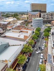 Aerial view of a modern cityscape featuring concrete, glass, and brick buildings.
