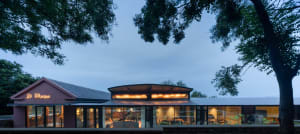 Modern cabin-style house with wooden walls, glass windows, and metal accents.