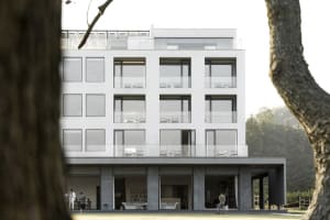 Modern apartment building with a concrete exterior and large glass windows.