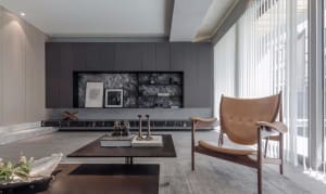 Modern minimalist living room with marble fireplace and wood accents, featuring a sleek coffee table and comfortable chair.
