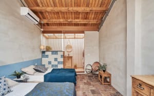Modern, minimalist bedroom with concrete walls and wooden ceiling beams.