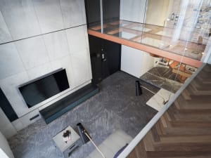 Modern living room with concrete walls, floor-to-ceiling windows, and minimalistic furniture.