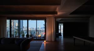 Modern living room with large glass windows overlooking a cityscape at dusk.