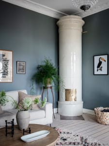 A modern living room featuring white tiled columns, a white sofa, potted plant, and decorative rug.