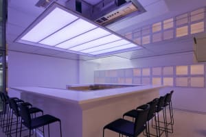 A stylish, modern bar with a concrete countertop and illuminated lighting above.