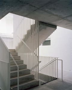 A modern, industrial-style staircase with concrete steps and white metal railings.