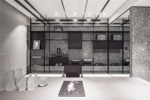 A clean, modern office space featuring concrete-textured walls, minimalist furniture, and a glass desk.