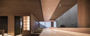 A sleek, modern restaurant bar with wooden accents, minimal lighting, and a spacious seating area.