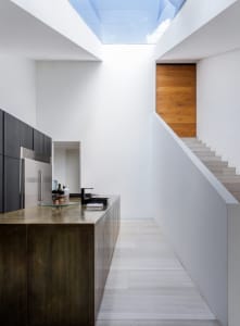 A modern minimalist kitchen with metallic finishes and white tiled flooring.