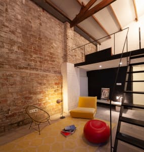 Industrial-style living room with exposed brick walls, concrete flooring, and modern furniture.