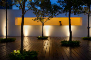 A contemporary outdoor space featuring a wooden deck and illuminated sconces, creating a serene atmosphere.