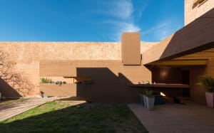 A modern architectural exterior with concrete walls and a concrete patio area with plants.