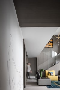 Modern living room with a minimalist design featuring a concrete floor and walls, accented by a colorful sofa and abstract wa