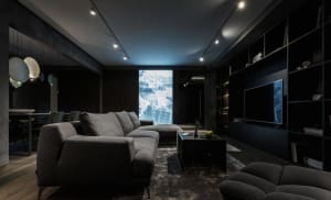 Industrial living room with concrete walls and floor, featuring a large sectional sofa, a coffee table with a laptop and an a