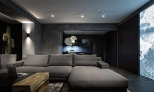 A stylish, modern living room with dark, concrete walls and a comfortable, oversized sofa.