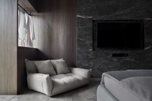 A modern bedroom featuring marble walls and wood accents.