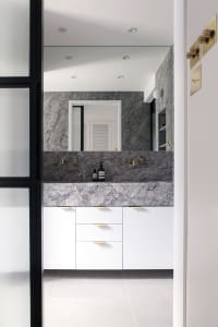 Modern bathroom featuring a marble countertop and vanity with white cabinets.