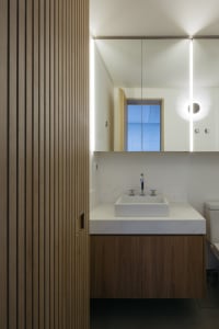 A modern bathroom featuring minimalist wood accents and a sleek white countertop sink.