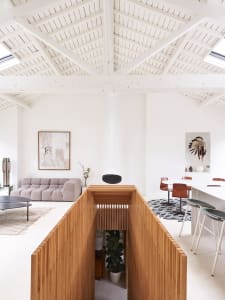 A modern living and dining room with wooden walls and white walls, featuring a wooden partition and a round coffee table in t