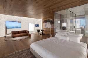A modern bedroom with wood paneling, white bedding, and a glass wall.