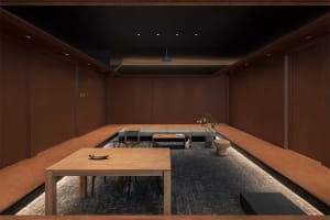 Modern restaurant interior with wooden tables and benches, concrete flooring, and minimalist design elements