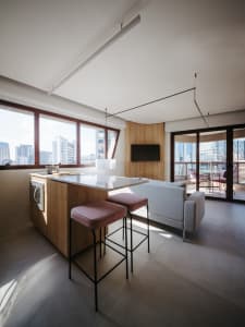 A modern kitchen with wooden cabinets, a white countertop, and a view of the city.