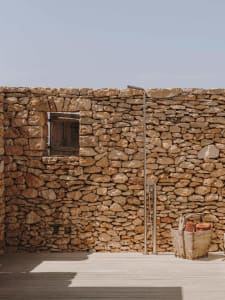 An outdoor shower with a stone wall and wooden floor.