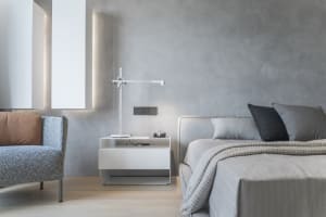A minimalist bedroom designed with concrete walls and a modern light fixture, featuring a comfortable bed with gray bedding a